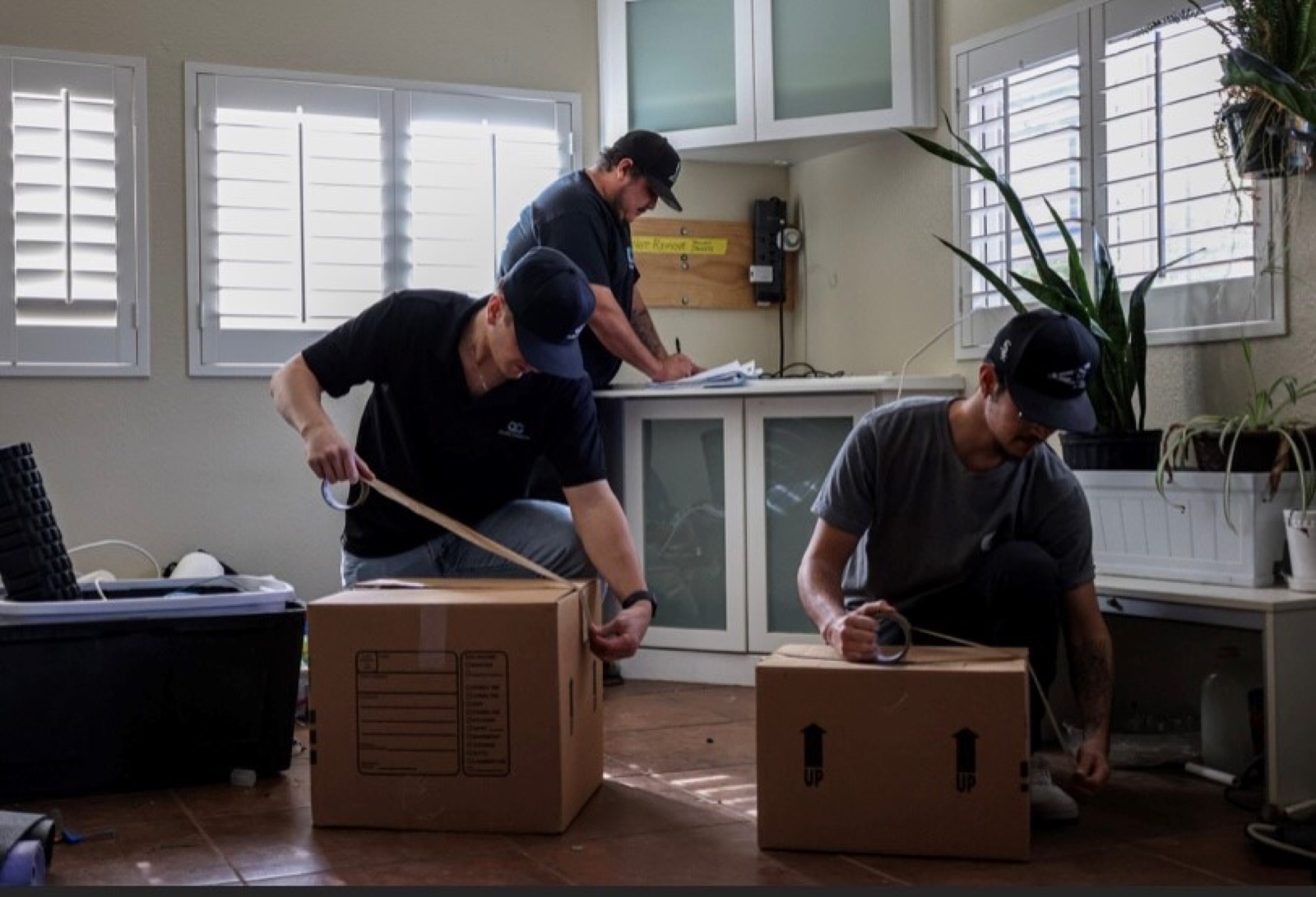 Three Quality Contents technicians boxing household belongings and writing a written inventory during a pack-out